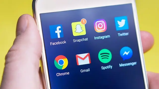 Person holding a smartphone with social media icons visible